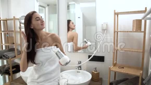 头发护理女人在浴室用吹风机烘干长发视频的预览图