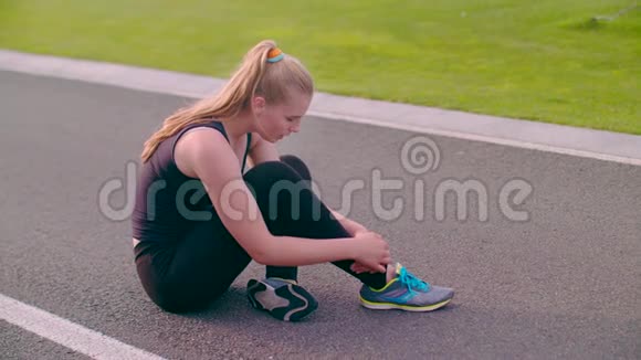 跑完马拉松后坐在沥青路上疲惫不堪的女人视频的预览图