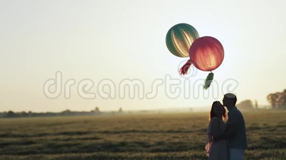 双手拿着氦气球走进田野在夕阳下牵手视频的预览图