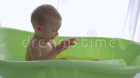 婴儿卫生可爱的小男孩在明亮的房间洗澡时泼水视频的预览图