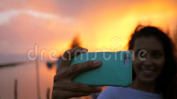 年轻的混血女人在美丽的夕阳下自拍女孩使用手机高清慢运动泰国视频的预览图