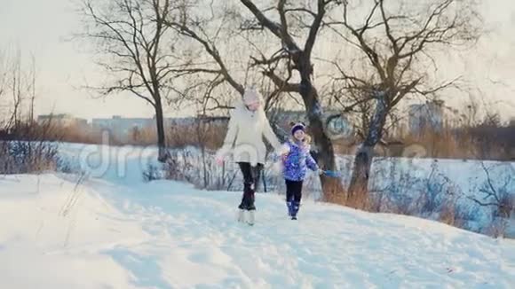 一个女人带着一个孩子在冬天的公园里笑女孩围着妈妈跑来跑去好好享受冬日视频的预览图
