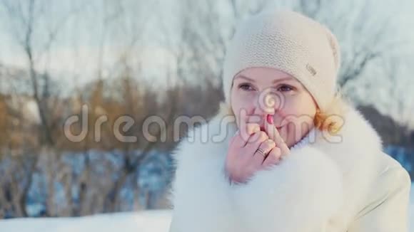 一个年轻女人的冬天画像微笑温暖的双手放在冰冷的手上视频的预览图