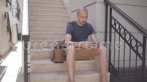 男人拿着包坐在楼梯的台阶上打电话视频的预览图