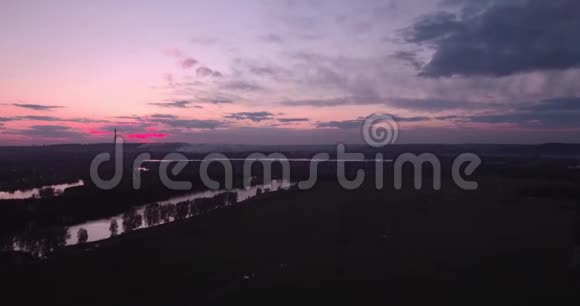 俯视图空气田野里的高压塔和地平线上的小镇晚霞中的云彩视频的预览图