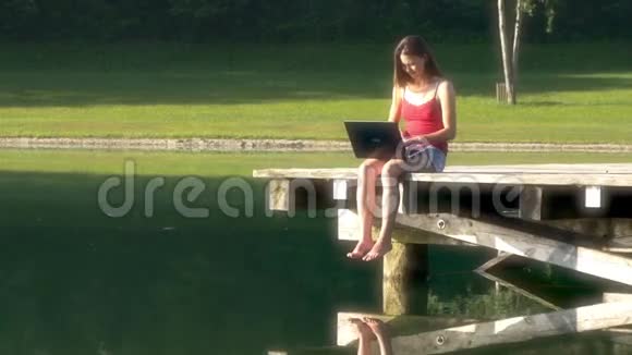 带笔记本电脑的女人在湖边度假视频的预览图