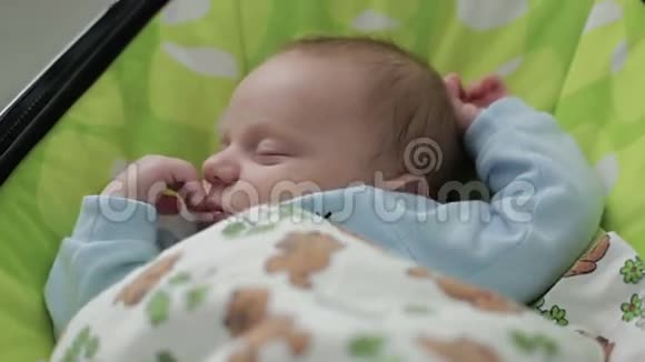 一个可爱的小男孩在绿色的摇篮里睡着了视频的预览图
