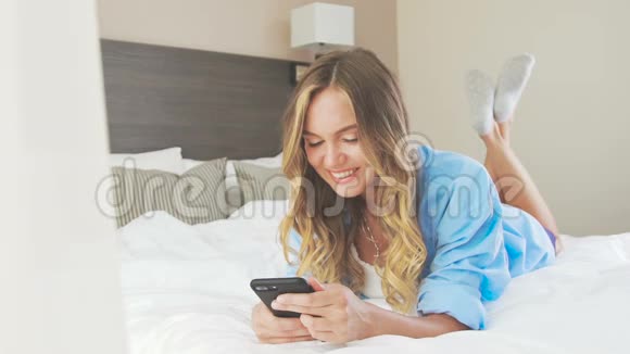 穿衬衫的女人躺在床上踢着脚做梦视频的预览图