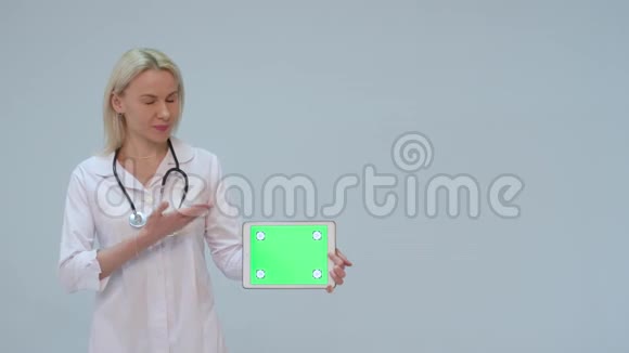 一位女医生的肖像白色外套和绿色屏幕的平板电脑视频的预览图