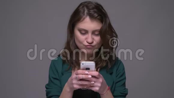 用灰色背景的手机拍摄成年有吸引力的黑发女性特写镜头视频的预览图