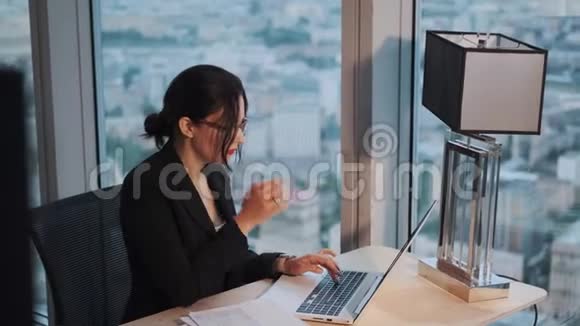 女人在办公室用笔记本电脑工作视频的预览图