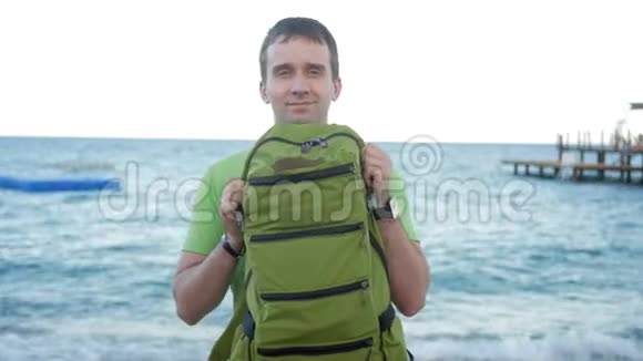 海滩上的人展示了一个绿色的背包对着相机微笑他转过身来把包给我看视频的预览图