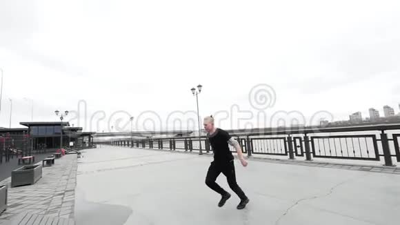 一个自由奔跑的追踪金发男人在公园里跳着翻板跑酷视频的预览图