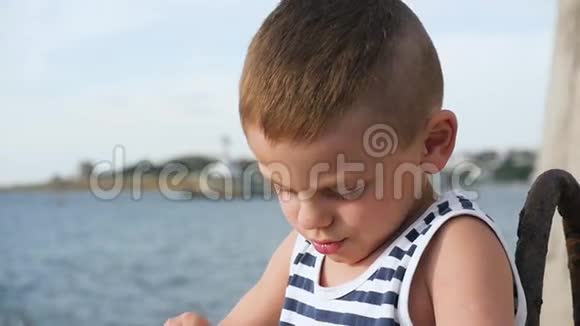 穿着条纹衬衫的小男孩拿着一副望远镜在大海前视频的预览图
