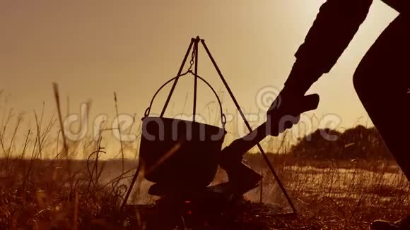 点燃篝火徒步旅行者停在营地徒步旅行者的水在水壶里沸腾保龄球锅在日落时点燃阳光视频的预览图