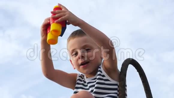 漂亮的小男孩在天空背景上玩玩具望远镜视频的预览图