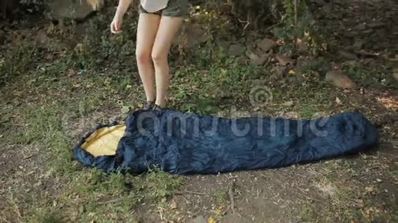 在营地的草地上放睡袋的年轻妇女视频的预览图