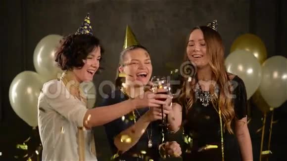三个女人在金色的彩纸中拥抱眼镜和欢笑享受生日聚会年轻的女士在这期间玩得开心视频的预览图