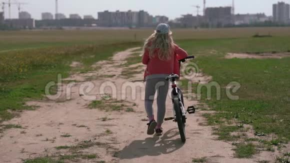 健康的生活方式骑自行车的女孩在城市附近的田野上行走视频的预览图