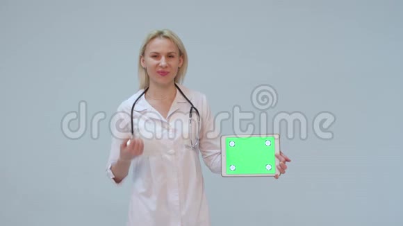 一位穿着白色外套平板电脑和听诊器微笑着看镜头的女医生的肖像视频的预览图