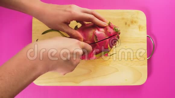 俯视图雌手用刀在木板上切果白龙果自然健康的概念视频的预览图