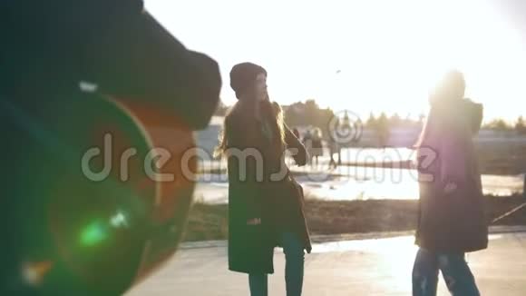 男人在女孩面前弹吉他日落时分在户外跳舞视频的预览图