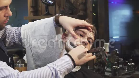 英俊的年轻人在理发店刮胡子视频的预览图