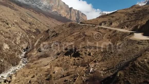 高加索山区有一条土路和一条山河的峡谷鸟瞰图晴天视频的预览图