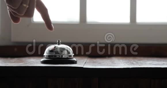 男子按响酒店接待铃男子按动住宿电话铃在木制接待前台视频的预览图