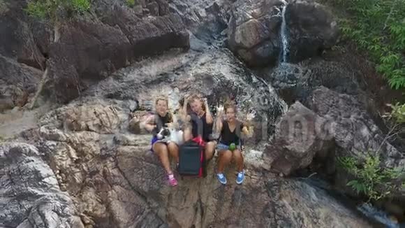 空中一群年轻的游客在瀑布前休息手在镜头中挥舞泰国视频的预览图