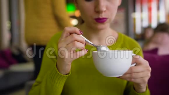 女人在咖啡屋里喝着加奶油的咖啡巧克力糖浆和勺子视频的预览图