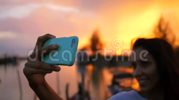 年轻的混血女人在美丽的日落时做自拍使用手机的女孩剪报高清慢速运动泰国视频的预览图