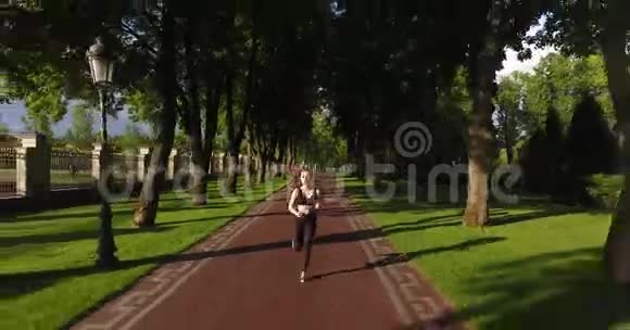 那个漂亮的运动女人正在阳光明媚的公园里慢跑前面的风景视频的预览图