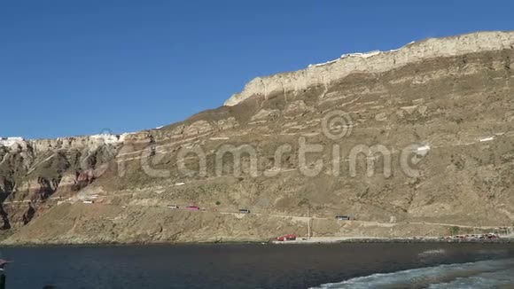 离开希腊圣托里尼岛的奥莫斯阿蒂诺斯港在背景巴士上沿着卡尔德拉墙朝菲拉行驶视频的预览图