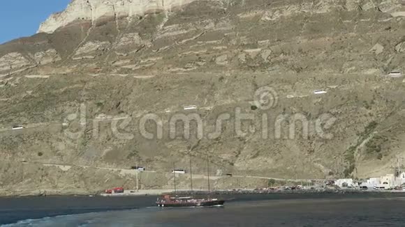 离开希腊圣托里尼岛的奥莫斯阿蒂诺斯港在背景巴士上沿着卡尔德拉墙朝菲拉行驶视频的预览图