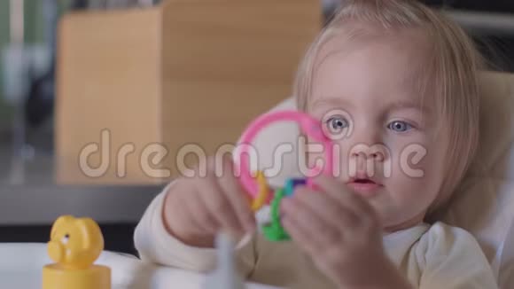 可爱的小女孩坐在桌子旁玩玩具对着相机微笑视频的预览图