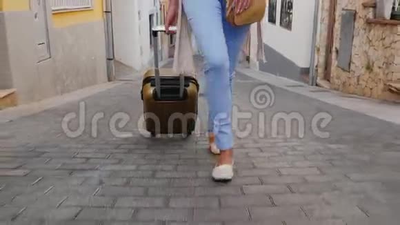一位游客走在欧洲老城狭窄的街道上在图片中可见的腿和旅行袋的车轮视频的预览图
