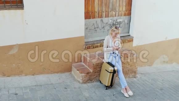 带电话的年轻女子坐在他的旅行袋旁边欧元旅费视频的预览图