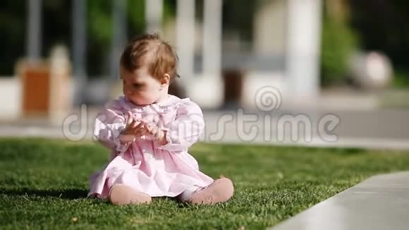 快乐的女婴坐在公园的绿草上玩耍视频的预览图