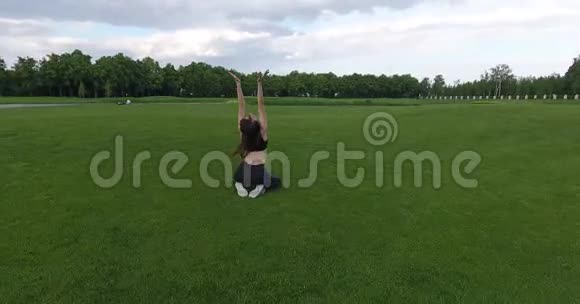 那个女人坐在草地上做普拉提和乔加圆的景色视频的预览图
