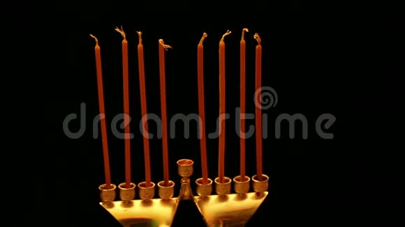 一个女人手里拿着一支燃烧的蜡烛她从蜡烛中点燃光明节的蜡烛一个女人从第一个点燃蜡烛视频的预览图