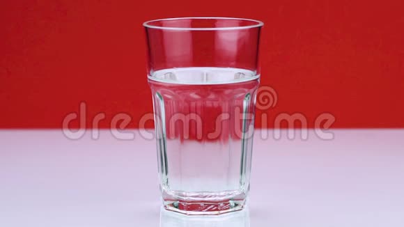 一粒止痛的泡腾药丸落入玻璃杯中在红色背景下溶解慢镜头的阿司匹林视频的预览图