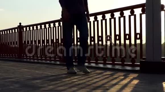 在斯隆莫桥上夕阳西下年轻人的双腿视频的预览图