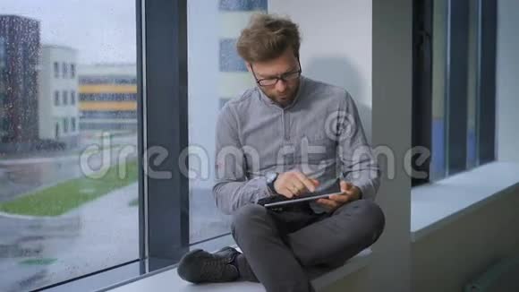 年轻求职者坐在窗前用平板电脑视频的预览图