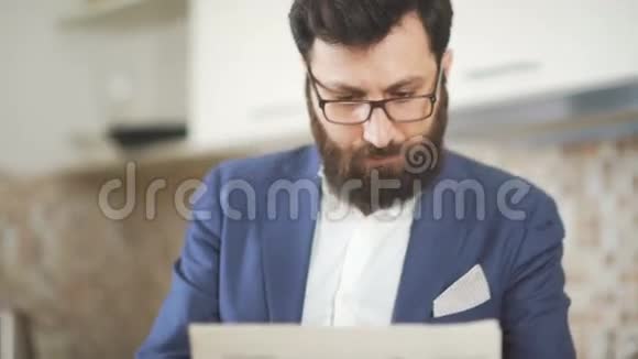 时尚的男人留着胡子戴着眼镜在家庭办公室看报纸视频的预览图