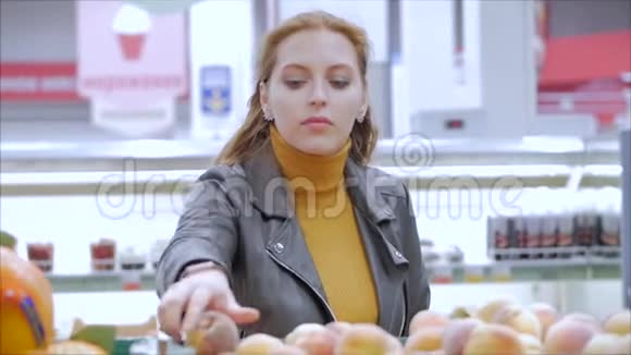 漂亮的年轻漂亮的红发女人在市场上在超市里买食物水果苹果西红柿橘子视频的预览图