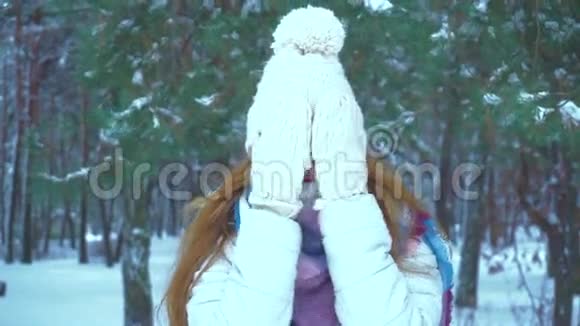 穿着温暖冬衣的女孩在冬天的森林里对着镜头微笑视频的预览图