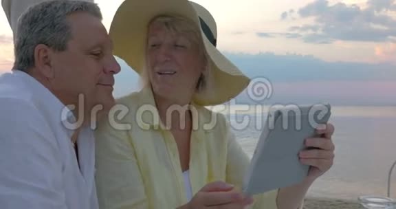 在海边使用触摸板的老夫妇视频的预览图