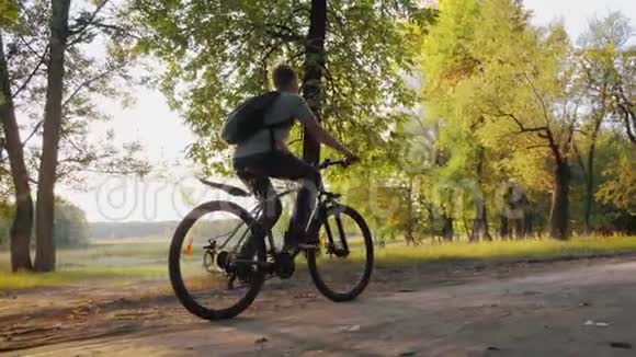 阳光明媚的一天十几岁的男孩在城市公园骑自行车健康的生活方式观念视频的预览图