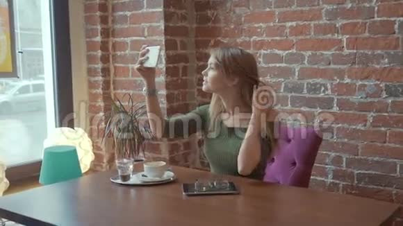 年轻漂亮的女人在手机摄像头上拍照时微笑着视频的预览图